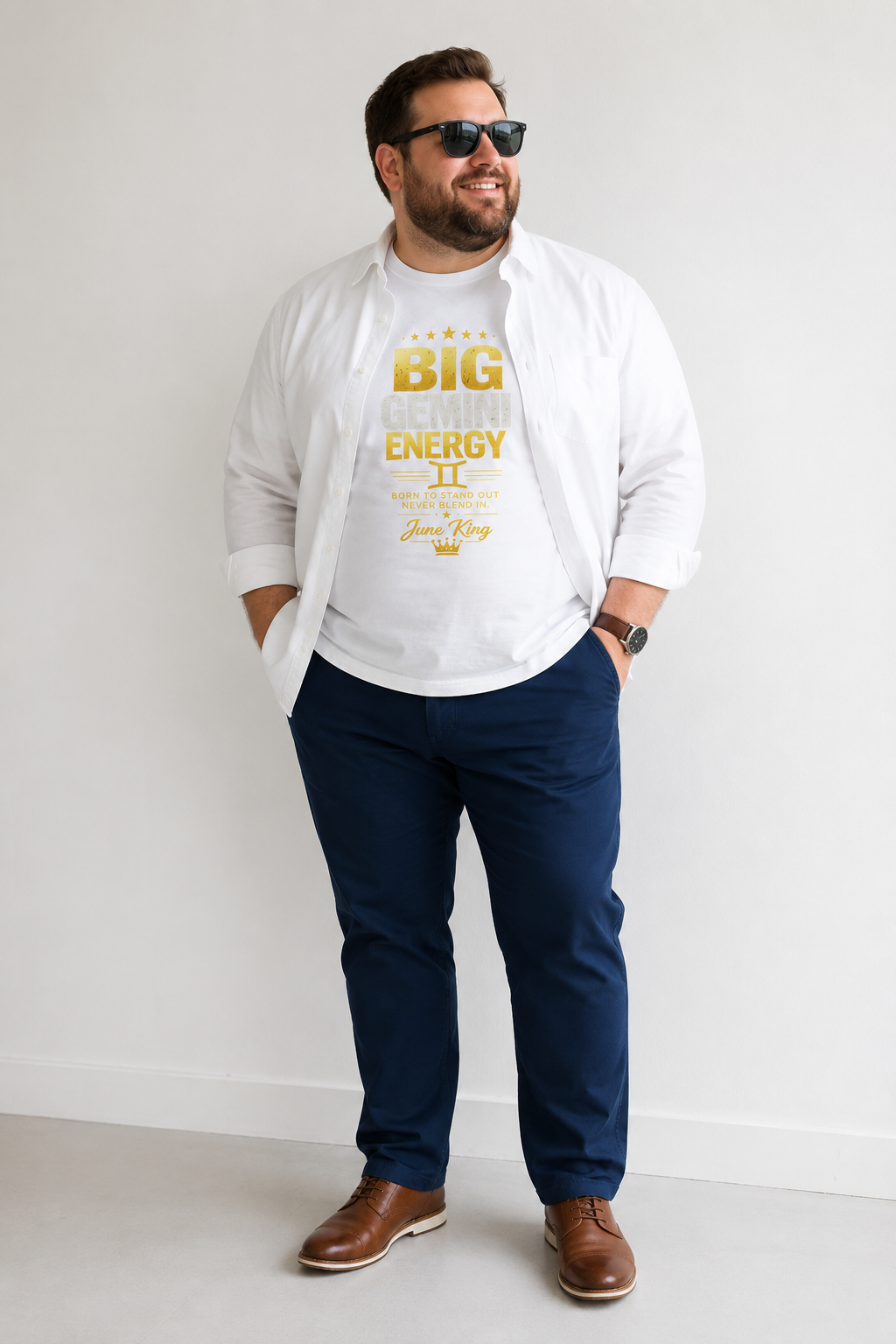 Man wearing a white hoodie with text, navy pants, and brown shoes on a plain background